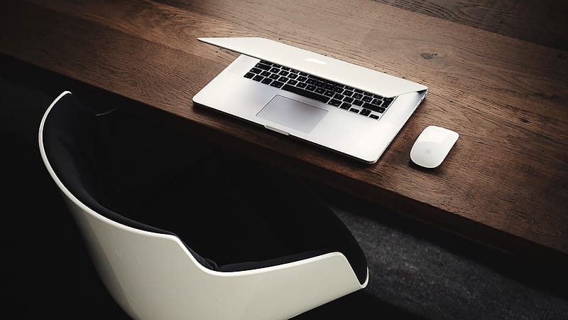 An empty office desk at the end of a working day, with a keyboard, a notebook and a switched-off monitor.