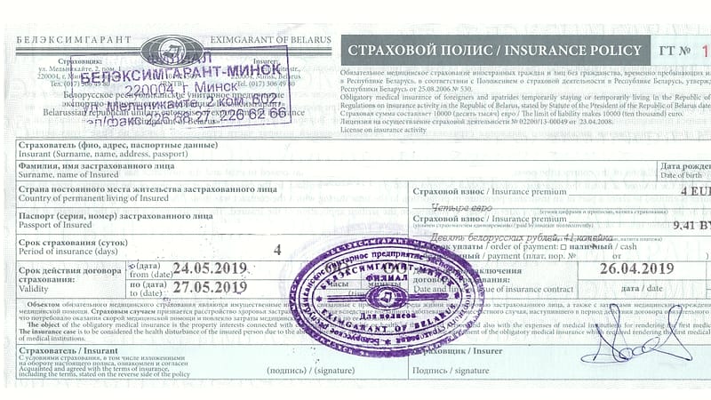 A printed insurance policy document with dense clauses and a stamped seal lying flat on a table.