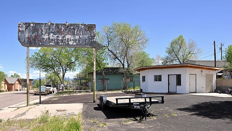 A disused roadside gas station with empty pump islands and a faded canopy under a wide desert sky.