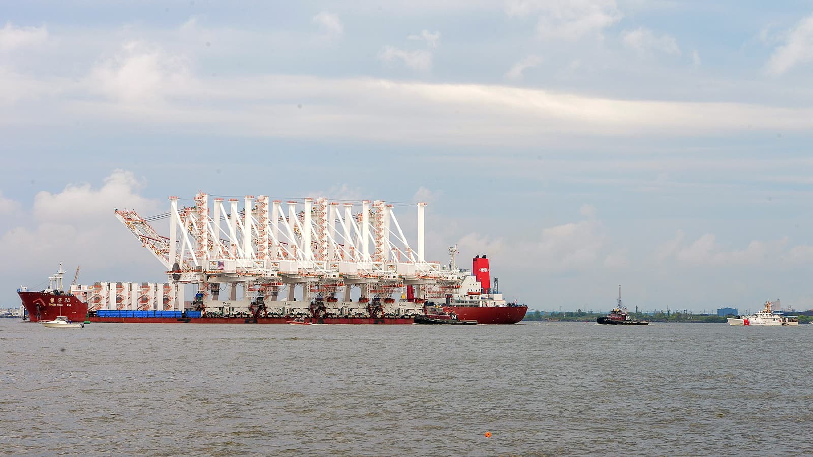 Container ship crew in overalls descend a gangway onto a quayside beside stacked containers.